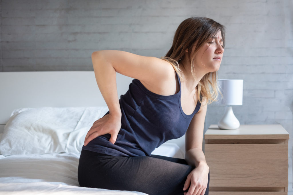 Woman sitting and holding back in pain